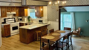 A spacious kitchen with wooden cabinets, a central island, and a dining area with a table and chairs.