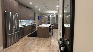 Eine moderne Küche mit Holzboden, Edelstahlgeräten und Pendelleuchten.