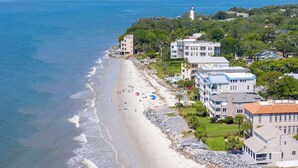 Ein Küstenhotel mit direktem Strandzugang, mehreren Gebäuden und einem Leuchtturm im Hintergrund.