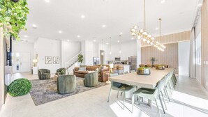 Zona d'estar àmplia amb una gran taula de dinar, mobles moderns i una escala cap a un pis superior.