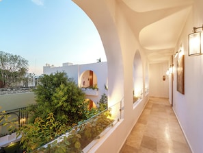 A corridor with white walls, glass railings, and a view of greenery and buildings. - Hotel Serenata Santa Lucia, Mérida (Mérida)