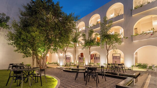A courtyard with hexagonal paving, outdoor seating, and trees. - Hotel Serenata Santa Lucia, Mérida (Mérida)