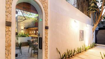 An outdoor dining area with stone walls, a wooden archway, and a seating arrangement.