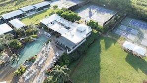 Ett flygbildsbild av ett semesterområde med en swimmingpool, tennisbanor och en restaurang.