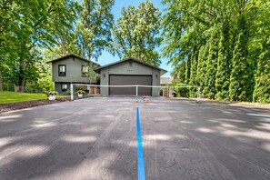 A volleyball court with a net, surrounded by trees and a building in the background.