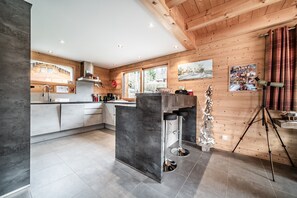 Eine moderne Küche mit einer zentralen Kochinsel, Holzwänden und großen Fenstern.