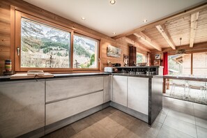 Eine moderne Küche mit großen Fenstern, Holzbalken und Bergblick.