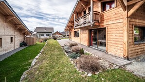 Ein holzhäuschen-artiges Gebäude mit Balkon, überdachter Veranda und gepflegtem Rasen.