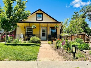 A yellow house with a front porch, a small garden, and a wooden fence. - Walk to Royal Gorge Railroad, River & Rafting Adventures! (Cañon City)