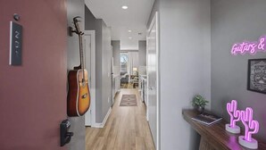 Un couloir décoré d’une guitare, d’un panneau lumineux au néon et d’un cactus.