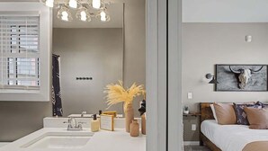 Une salle de bain moderne avec un grand miroir, un lavabo blanc et des plantes décoratives.