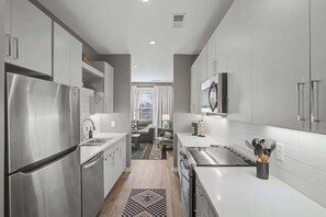 A modern kitchen with stainless steel appliances, white cabinetry, and a central island. - 2BR Condo in Walkable Area & 5 mins to Broadway! (Nashville)