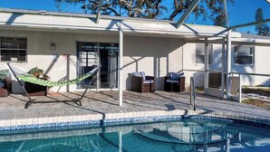 Un espace piscine agrémenté d’un hamac, de deux fauteuils en osier et d’une terrasse couverte.