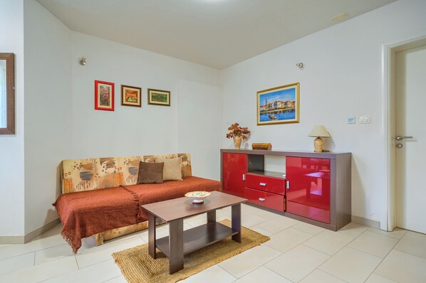 A living room with a sofa, a coffee table, a red cabinet, and wall-mounted pictures. - Comfortable apartments Obad, 4 min walk to Znjan beach (Split)
