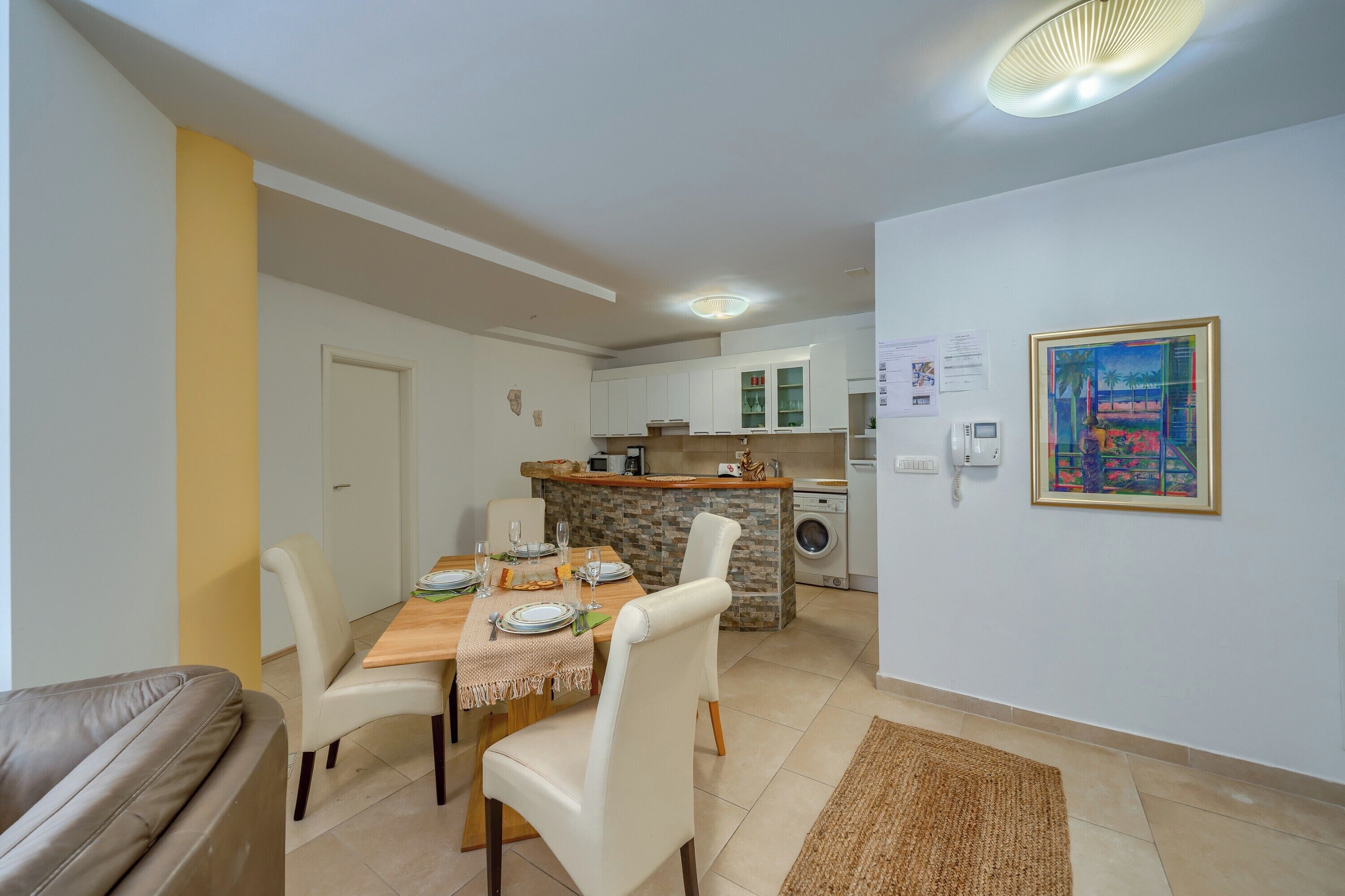 A modern kitchen with white cabinets, a central island, and a built-in washing machine.