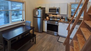 A kitchen with a dining table, a refrigerator, an oven, and a microwave.