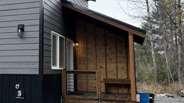 Un esterno in legno con una sezione rivestita in scuro e una finestra e una porta.