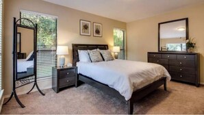 Une chambre à coucher comprenant un lit, des tables de chevet, une commode et un miroir.