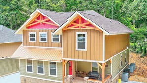 A two-story house with a front porch, stone foundation, and a red door. - Break Time - Modern 5BR with hot tub, game room, air hockey and resort pool (Gatlinburg)