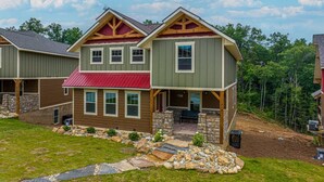 A two-story house with a red roof, stone foundation, and a stone pathway leading to the entrance.