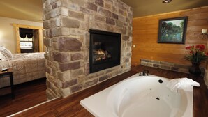 Ein Badezimmer mit Kamin aus Stein, einer großzügigen Badewanne, Holzwänden und einem Gemälde.