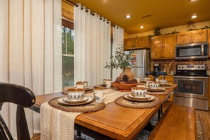 A dining area with a wooden table set for four, surrounded by chairs. - Hilltop Haven – 4BR Chalet with Indoor Pool, Theater Room, Sauna and Hot Tub (Gatlinburg)