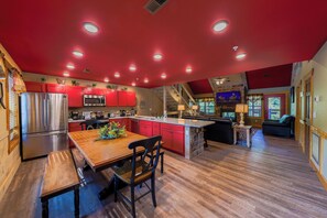 A spacious kitchen with red cabinets, a wooden dining table, and a central island.