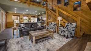 A spacious living room with a wooden staircase, a sofa set, and a coffee table.
