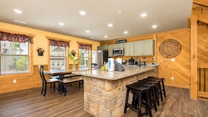 A kitchen with a stone island, wooden cabinets, and a view of the outside.