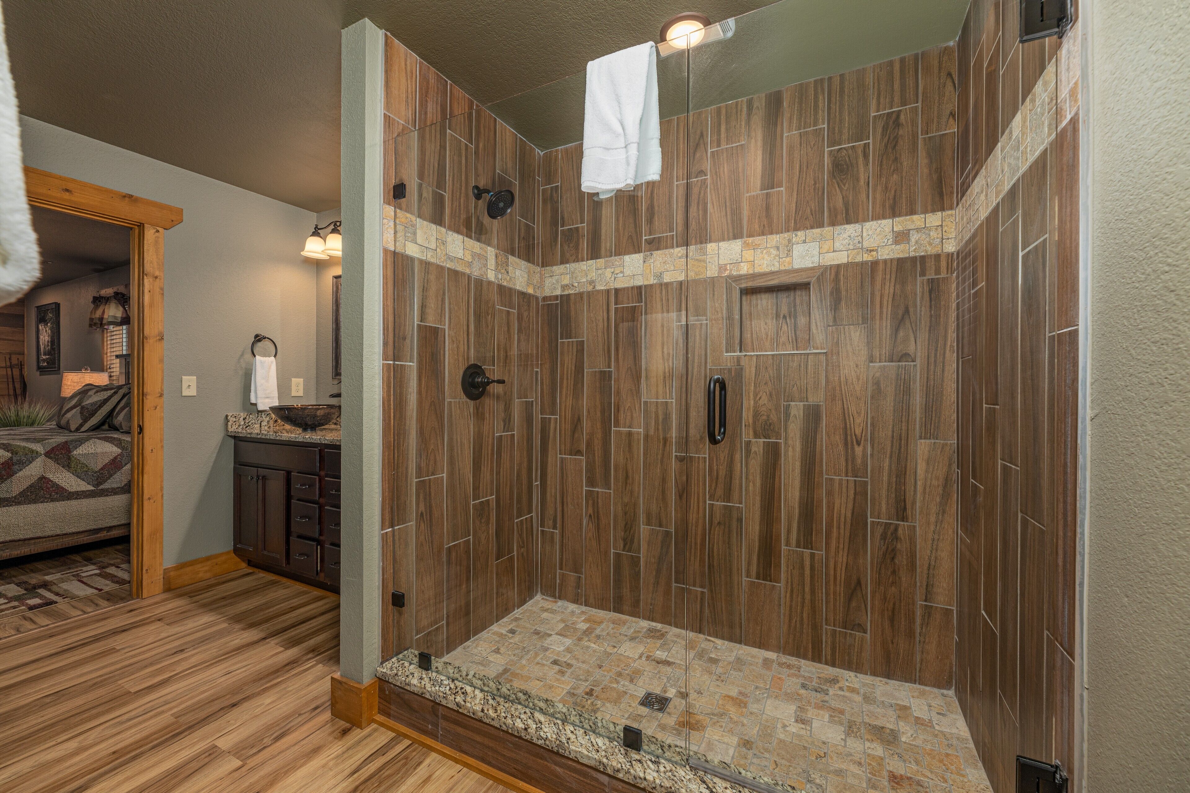 A spacious shower area with wooden paneling and a stone-tiled floor.