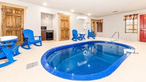 A swimming pool with blue chairs, a red door, and wooden cabinets.