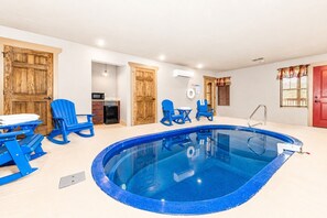 En swimmingpool med blå stolar, en röd dörr och träskåp.