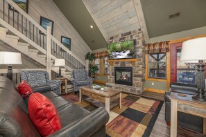 A spacious living room with a fireplace, a staircase, and a cozy seating area. - Wet & Wild – Luxury 4BR Chalet w/ Indoor Pool, Theater, Game Room & Hot Tub (Gatlinburg)