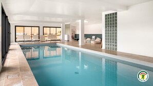 Ein Hallenbad mit Liegestühlen und einer Fliesenwand.