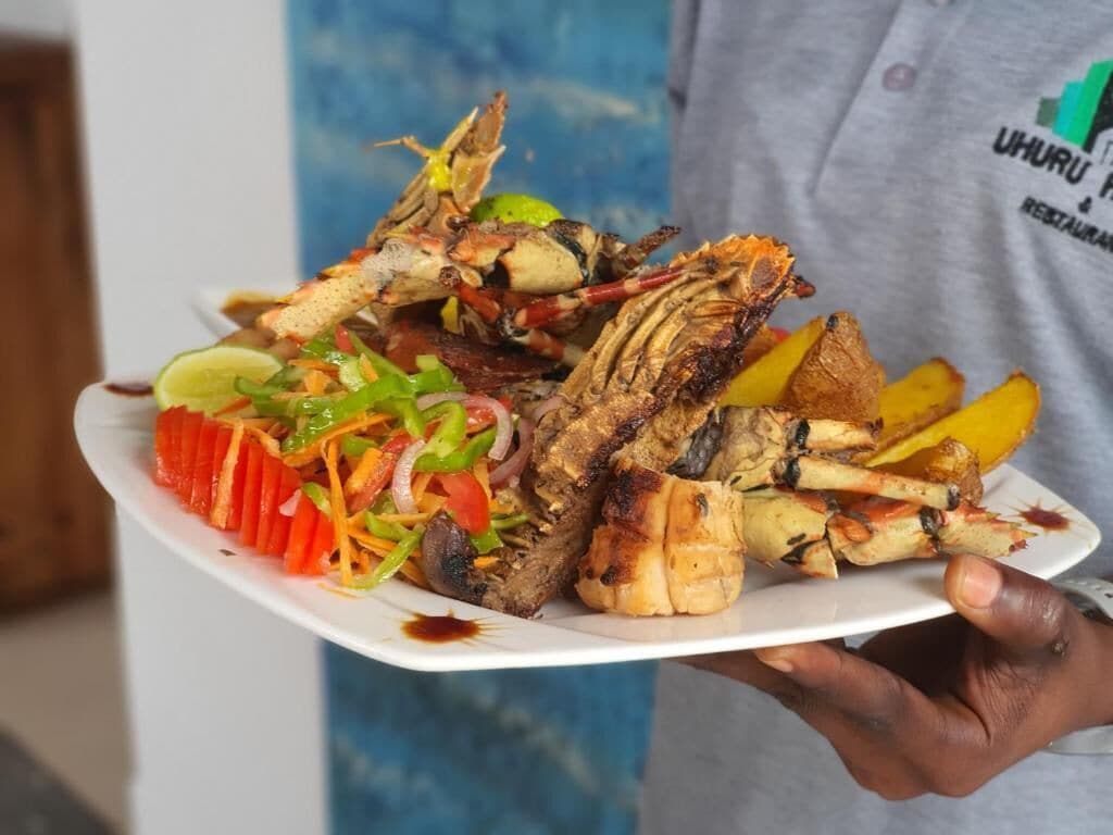 A person holding a plate with grilled seafood and vegetables.