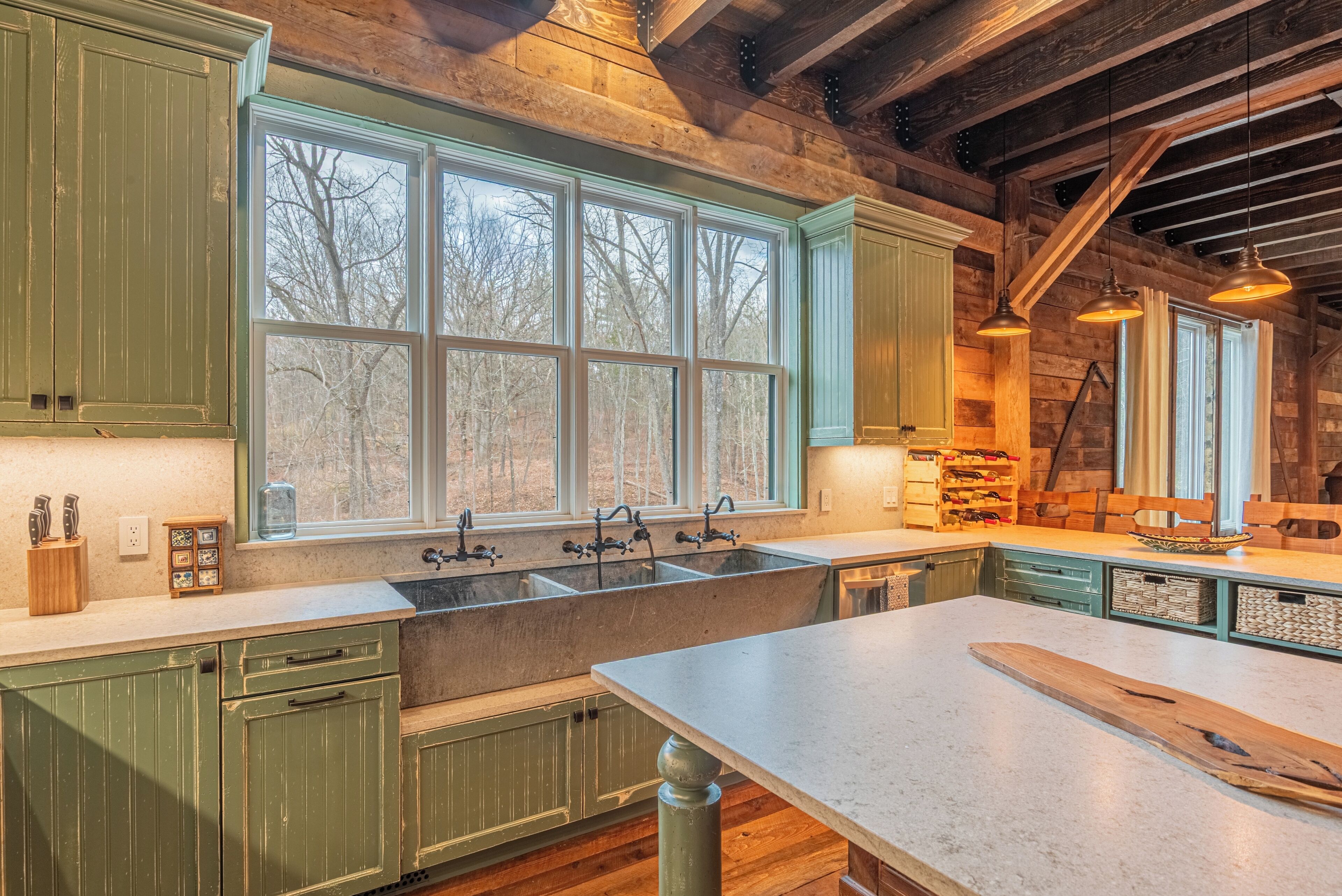 A rustic kitchen with wooden cabinets, a large window, and a stone countertop.