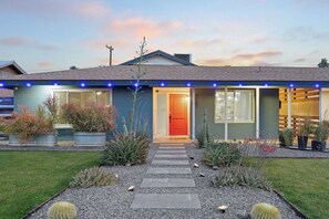 Ein modernes Haus mit roter Tür, Blumentöpfen und einem Kiesweg.