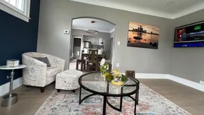 A living room with a round coffee table, patterned armchairs, a small side table, and a painting on the wall.