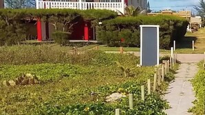 A house with a red roof and white exterior, surrounded by a garden and a pathway. - Comfortable beachfront retreat, 1 minute walk. Secure condominium - Orla 500 (Cabo Frio)