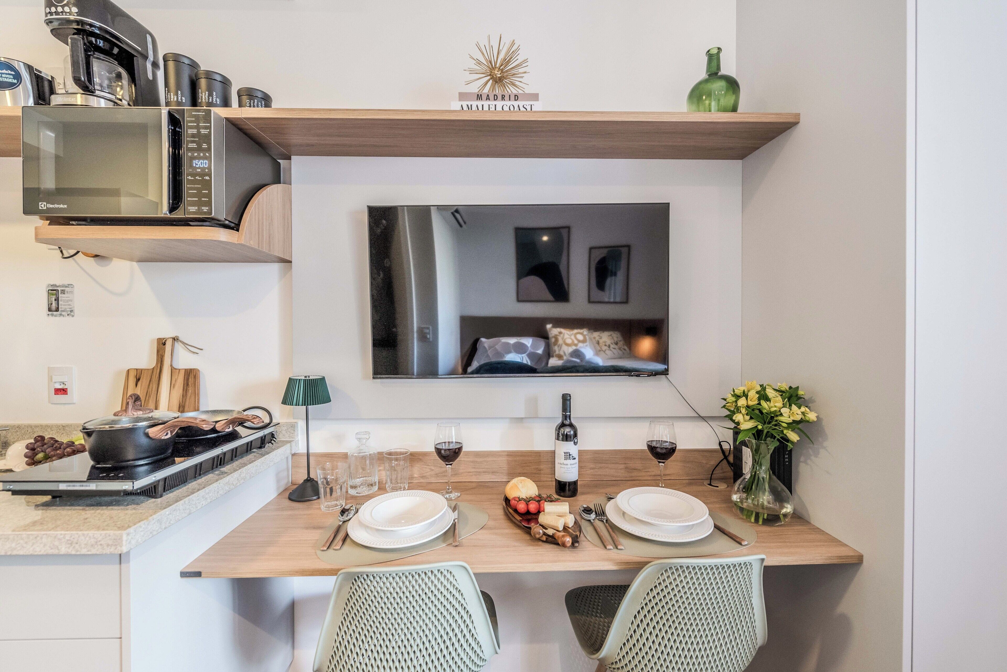 Cozinha moderna com micro-ondas, fogão e mesa de jantar posta para dois.