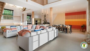 Un vaste espace de vie comprenant un grand canapé, une table à manger et un escalier.