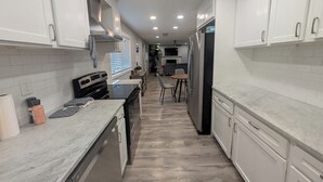 A modern kitchen with white cabinets, a black stove, and a wooden floor. - Charming 3-bedroom cottage by downtown Atlanta (Atlanta)