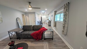 A modern living room with a sectional sofa, a coffee table, and a dining area in the background. - Charming 3-bedroom cottage by downtown Atlanta (Atlanta)