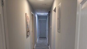 A hallway with a wooden floor, white walls, and a door at the end. - Charming 3-bedroom cottage by downtown Atlanta (Atlanta)