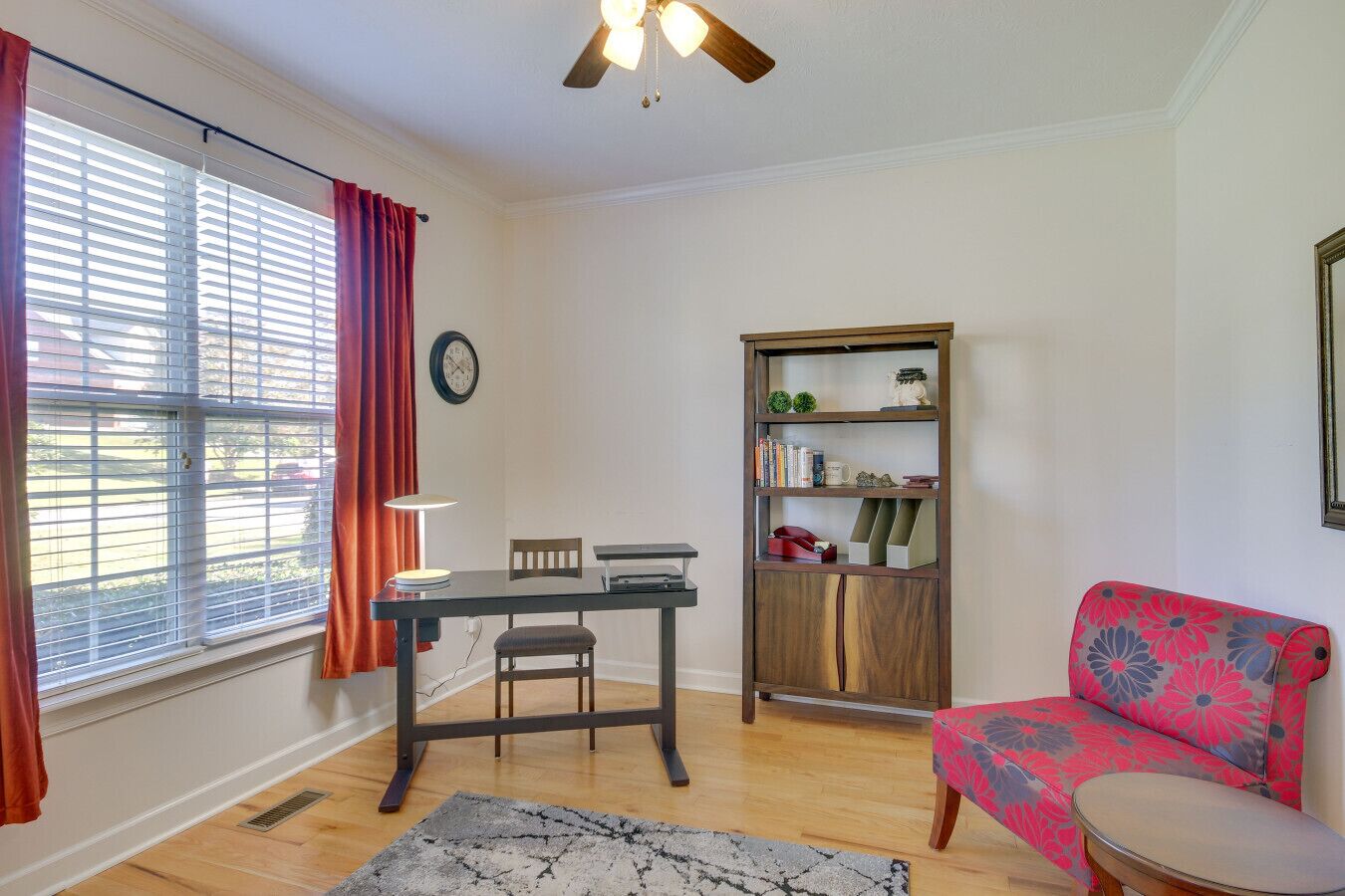 A living room with a dining table, a bookshelf, a sofa, and a ceiling fan.