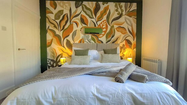 Een net opgemaakt bed met witte lakens en een decoratief hoofdeinde.