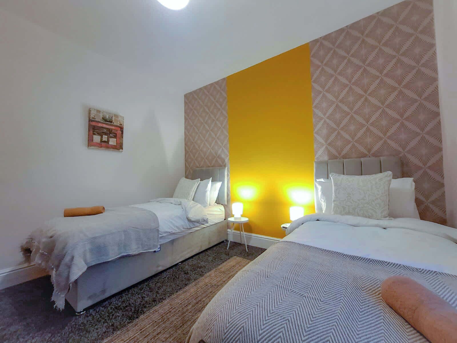 Ein Hotelzimmer mit zwei Betten, einem Nachttisch und einer Wand mit geometrischem Muster.