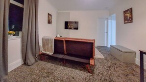 Een woonkamer met een bank, een televisie en een raam met gordijnen.