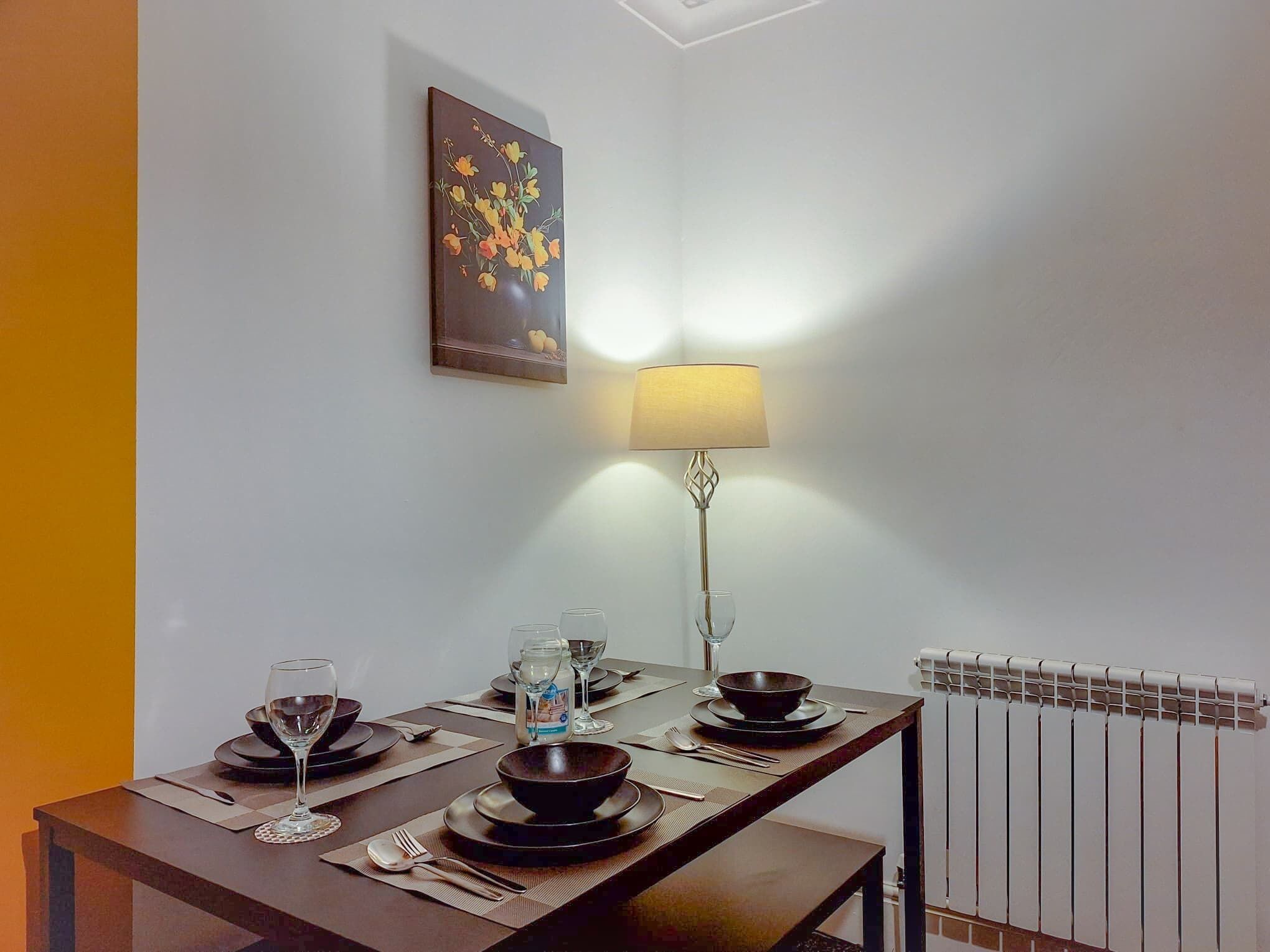 Ein Essbereich mit einem Tisch für zwei Personen, einer Lampe und einer Heizung.