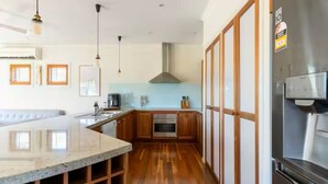 A modern kitchen with wooden cabinets, a stainless steel refrigerator, and a marble countertop. - Cascade Cottage: Spacious Family Retreat in Keysborough Garden Parking Sleeps 8 (Keysborough)